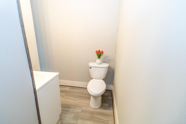 bathroom featuring wood finished floors, vanity, toilet, and baseboards