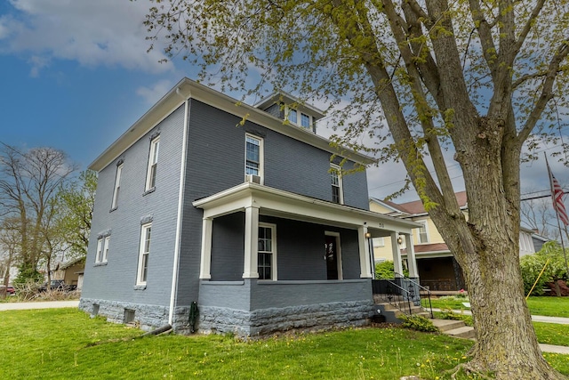 american foursquare style home with brick siding, a porch, and a front lawn