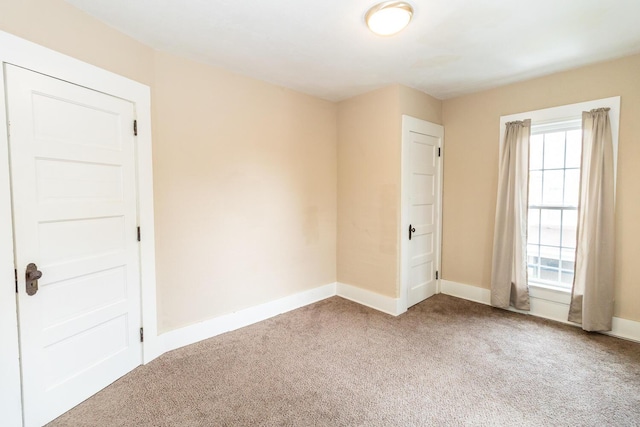 carpeted empty room featuring baseboards