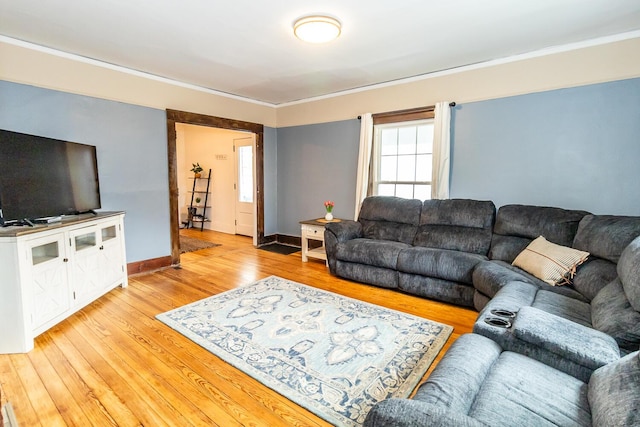living room featuring crown molding, baseboards, and light wood-type flooring