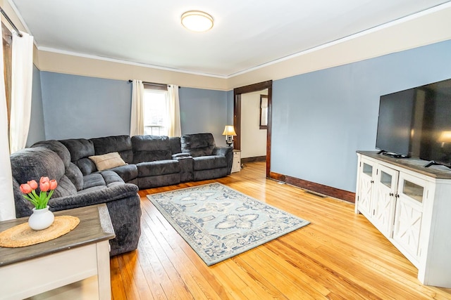 living area featuring visible vents, crown molding, baseboards, and light wood-style floors
