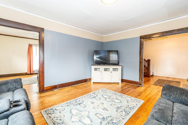 living room with wood finished floors, crown molding, and baseboards