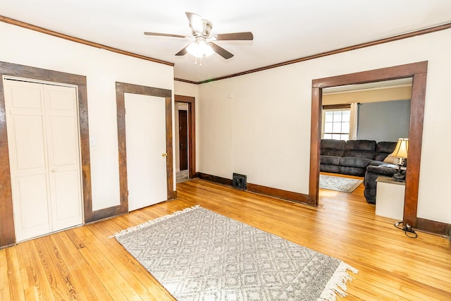 unfurnished bedroom featuring ornamental molding, ceiling fan, light wood-style flooring, and baseboards