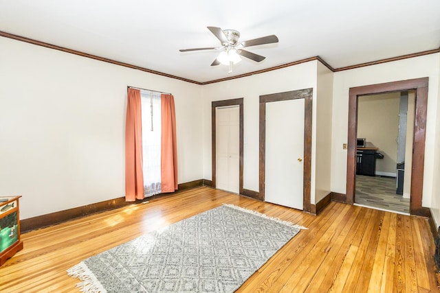 unfurnished bedroom with ornamental molding, light wood-style flooring, multiple closets, and baseboards