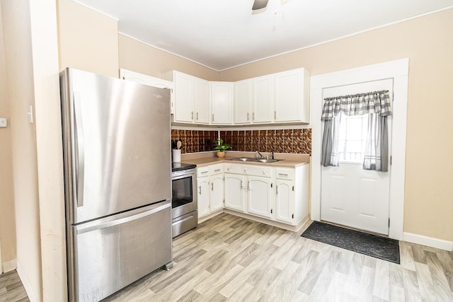 kitchen with a sink, tasteful backsplash, light countertops, white cabinets, and appliances with stainless steel finishes
