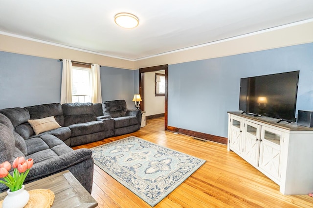 living room featuring a healthy amount of sunlight, light wood-type flooring, crown molding, and baseboards