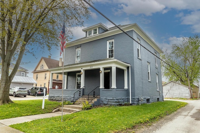 american foursquare style home with covered porch, a front yard, and brick siding