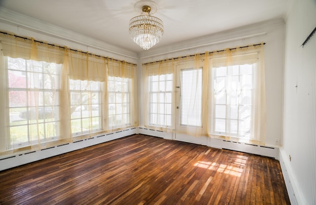 unfurnished room with a chandelier, dark wood finished floors, baseboards, and ornamental molding