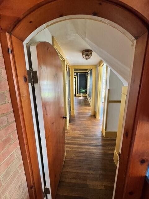 corridor with brick wall and wood-type flooring