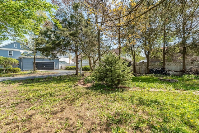 view of yard with fence, aphalt driveway, and a garage