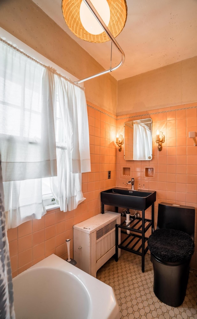 full bathroom with tile walls and a sink