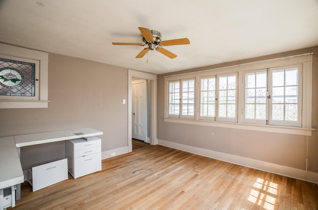 unfurnished office featuring baseboards, a ceiling fan, and light wood-style flooring