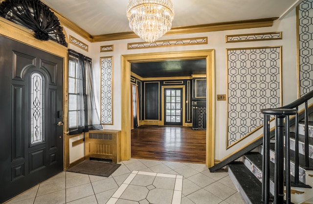 foyer with radiator heating unit, stairs, ornamental molding, light tile patterned floors, and a notable chandelier
