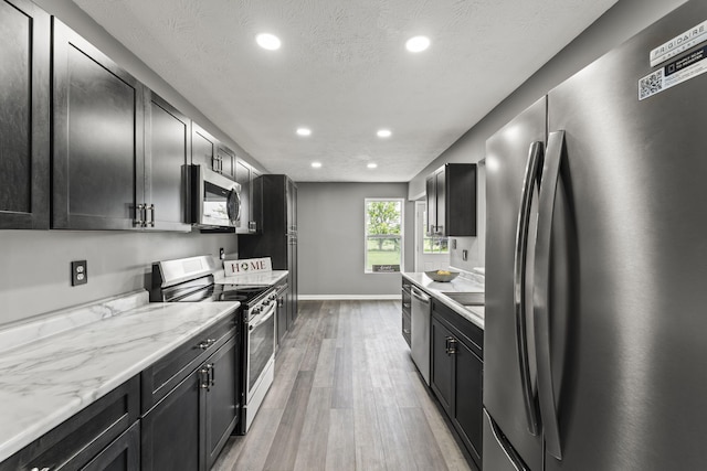 3667 Randee Ln, Springfield, OH 45502 - kitchen featuring stainless steel appliances, light wood-style floors, dark cabinets, recessed lighting, and light stone countertops