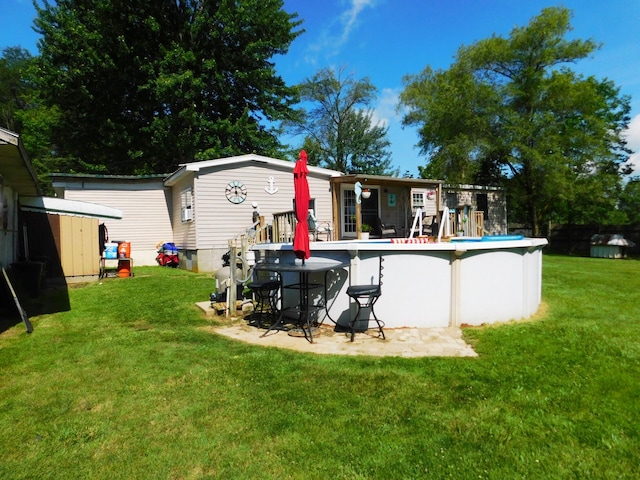 back of property with a storage shed, an outdoor structure, a yard, and an outdoor pool