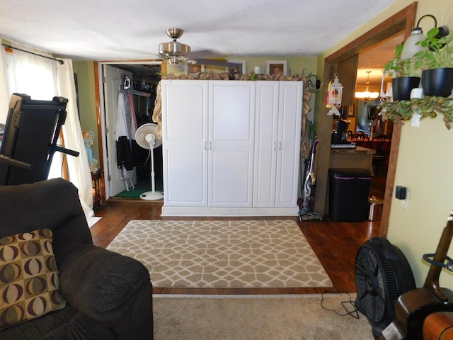 living room with ceiling fan with notable chandelier and dark wood-style flooring