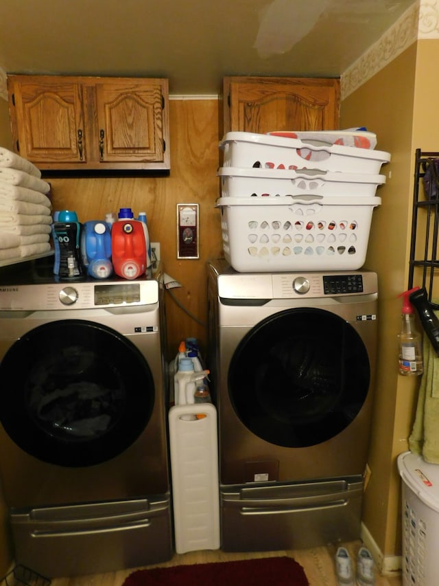 clothes washing area featuring cabinet space and washer and clothes dryer