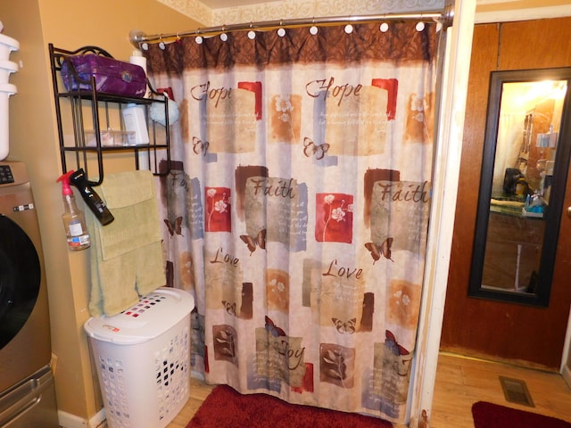 full bathroom with visible vents, a shower with shower curtain, and wood finished floors