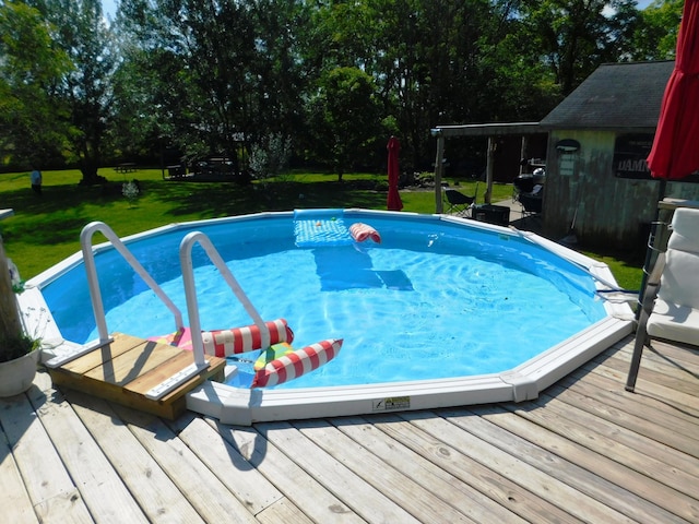 outdoor pool with a wooden deck and a yard