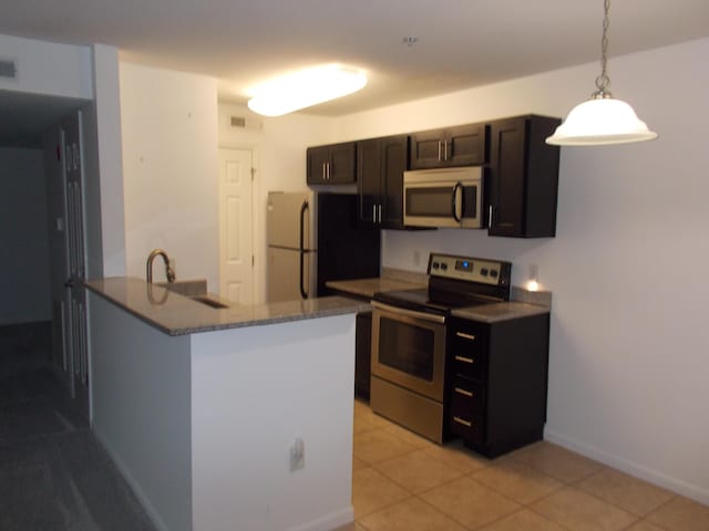 1145 W Bank Unit 106, Celina, OH 45822 - kitchen featuring appliances with stainless steel finishes, hanging light fixtures, light tile patterned flooring, a peninsula, and dark stone counters
