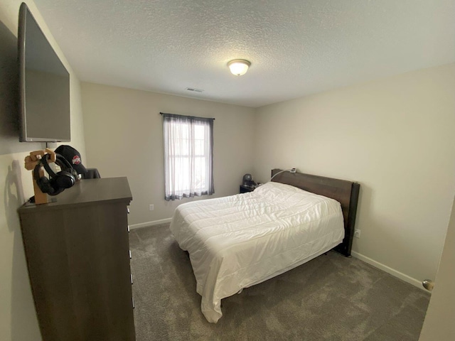 bedroom with baseboards, visible vents, dark carpet, and a textured ceiling