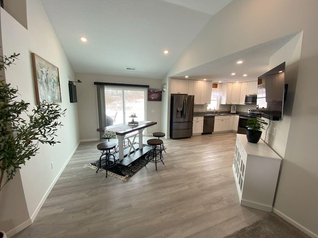 kitchen featuring stainless steel appliances, white cabinets, light wood-style floors, and baseboards