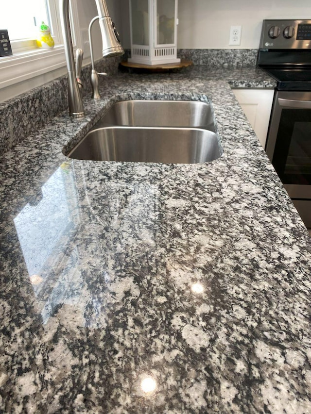 details with electric range, glass insert cabinets, white cabinets, a sink, and dark stone counters