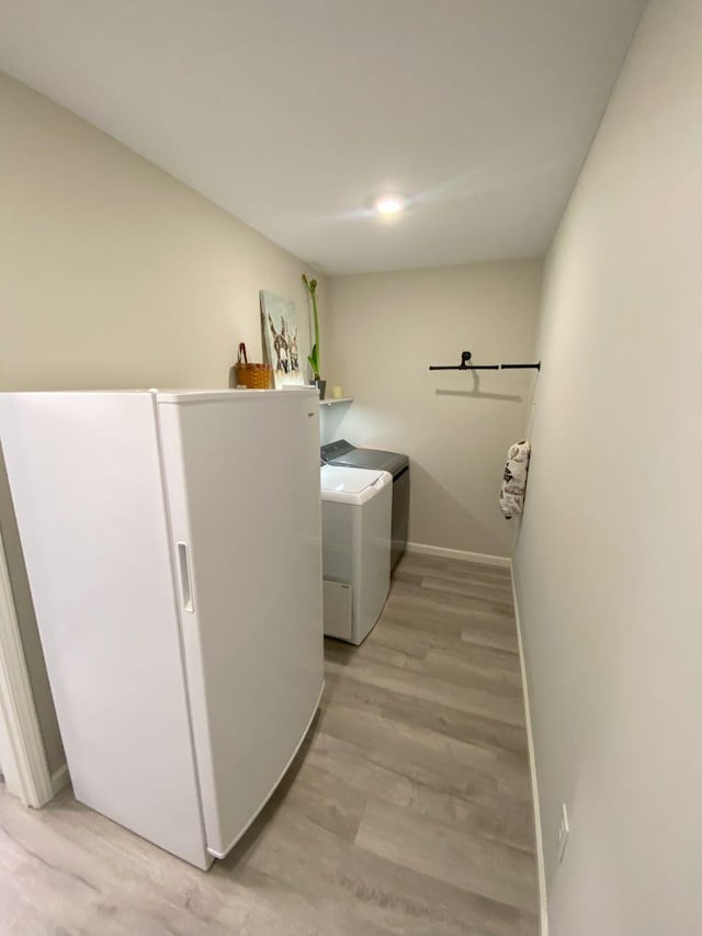 laundry room with light wood-style floors, laundry area, baseboards, and separate washer and dryer