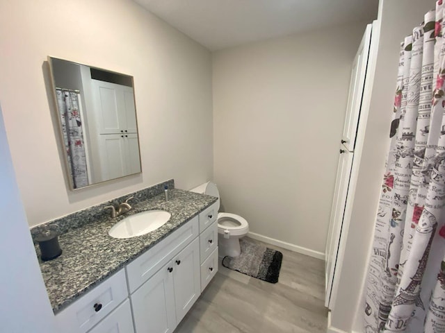 bathroom featuring toilet, wood finished floors, vanity, and baseboards