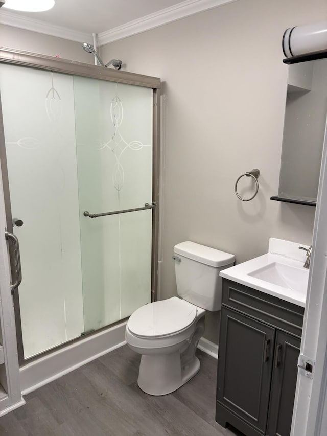 full bathroom featuring a shower stall, wood finished floors, vanity, toilet, and ornamental molding
