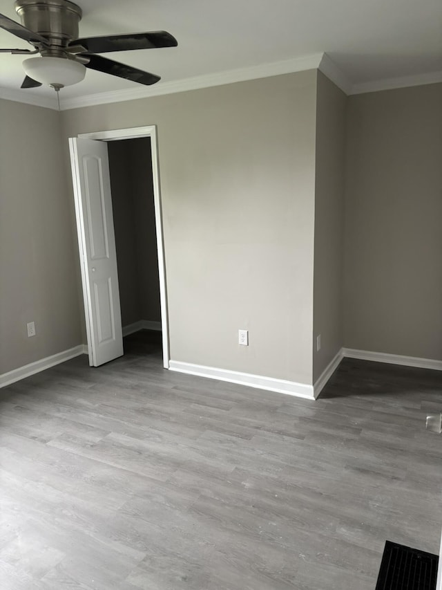 unfurnished room with baseboards, ornamental molding, ceiling fan, and wood finished floors