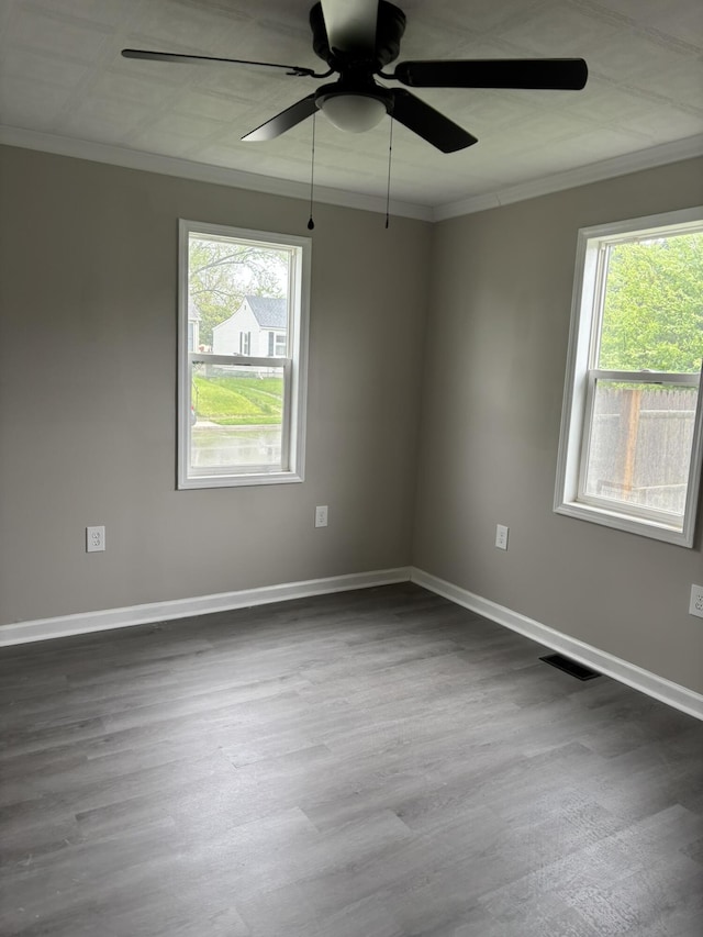 spare room with baseboards, ornamental molding, a ceiling fan, and dark wood-type flooring