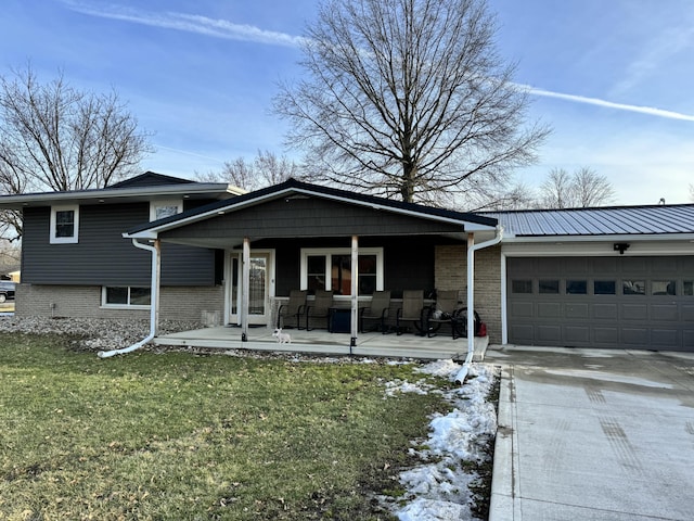 view of front of property featuring an attached garage, covered porch, brick siding, driveway, and a front yard