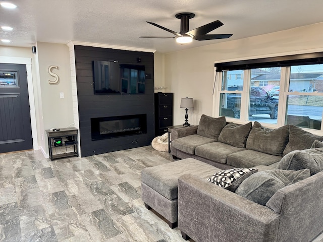 living area with a large fireplace, ceiling fan, and a textured ceiling