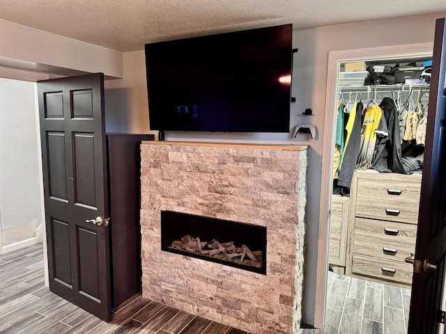 interior space featuring a textured ceiling, wood finish floors, a fireplace, and baseboards