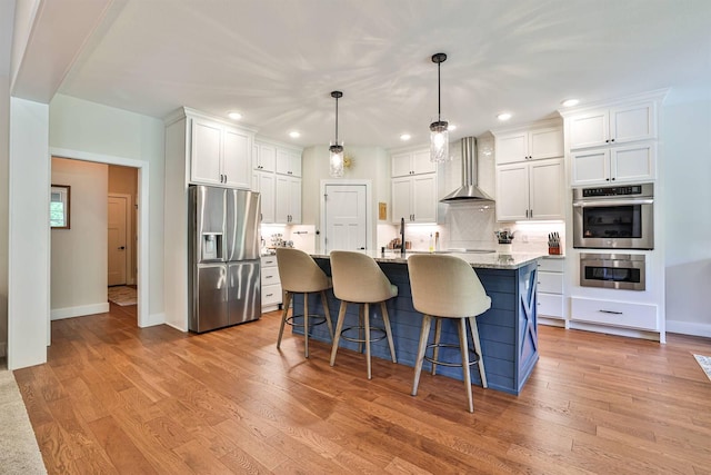 1439 Legacy Ct, Troy, OH 45373 - kitchen featuring stainless steel appliances, wall chimney range hood, white cabinets, recessed lighting, and light wood-style floors