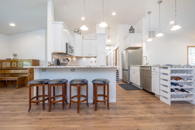 9342 State Route 368, Huntsville, OH 43324 - kitchen with appliances with stainless steel finishes, a peninsula, vaulted ceiling, white cabinetry, and backsplash