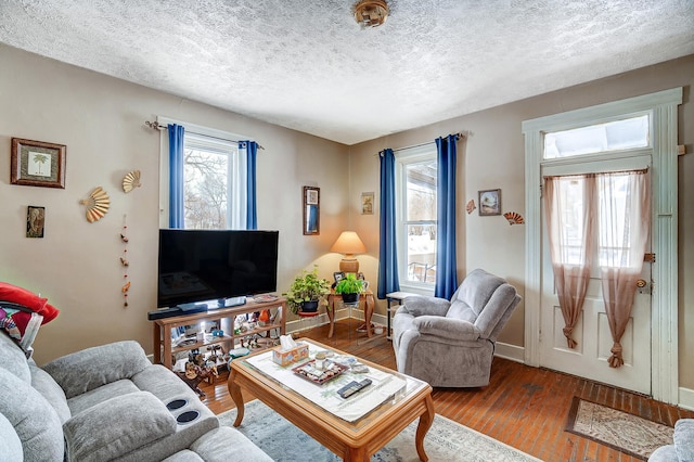 living area with a textured ceiling, baseboards, and wood finished floors