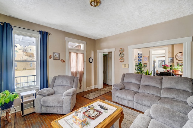 living room with a textured ceiling, dark wood finished floors, and baseboards