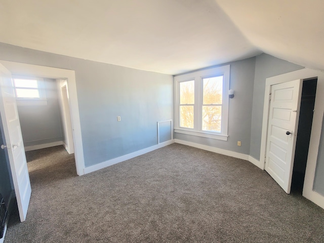 unfurnished bedroom featuring vaulted ceiling and dark carpet