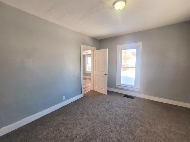 spare room with dark colored carpet