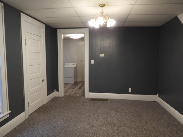 carpeted empty room with a paneled ceiling, washer / clothes dryer, and a chandelier