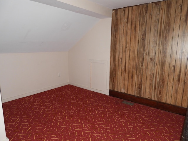 additional living space featuring vaulted ceiling and dark colored carpet