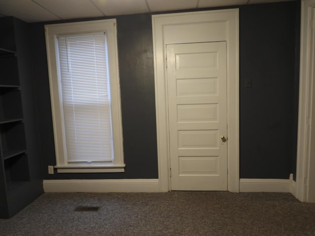 interior space featuring a paneled ceiling and carpet flooring