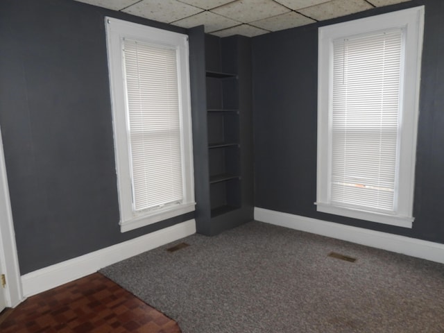 empty room with carpet and a drop ceiling