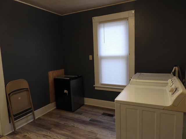 clothes washing area with dark hardwood / wood-style flooring, ornamental molding, and independent washer and dryer