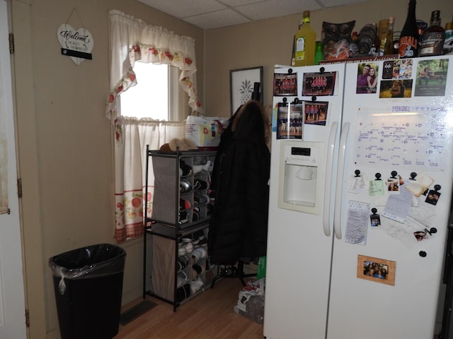 kitchen with hardwood / wood-style flooring, white fridge with ice dispenser, and a drop ceiling