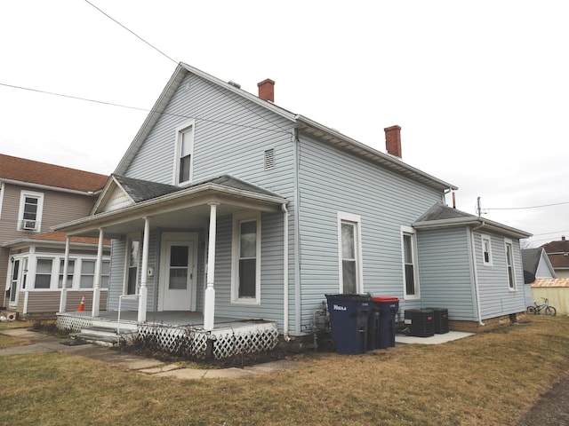 rear view of house featuring a lawn, central air condition unit, and a porch