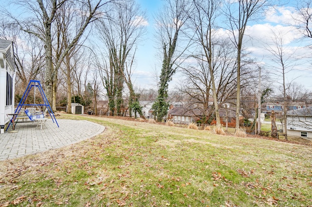 view of yard featuring a storage shed, a playground, a patio, and an outbuilding