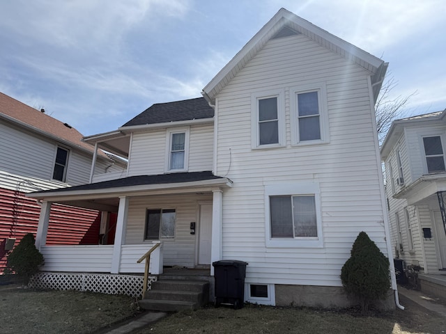 view of front facade featuring roof with shingles and covered porch